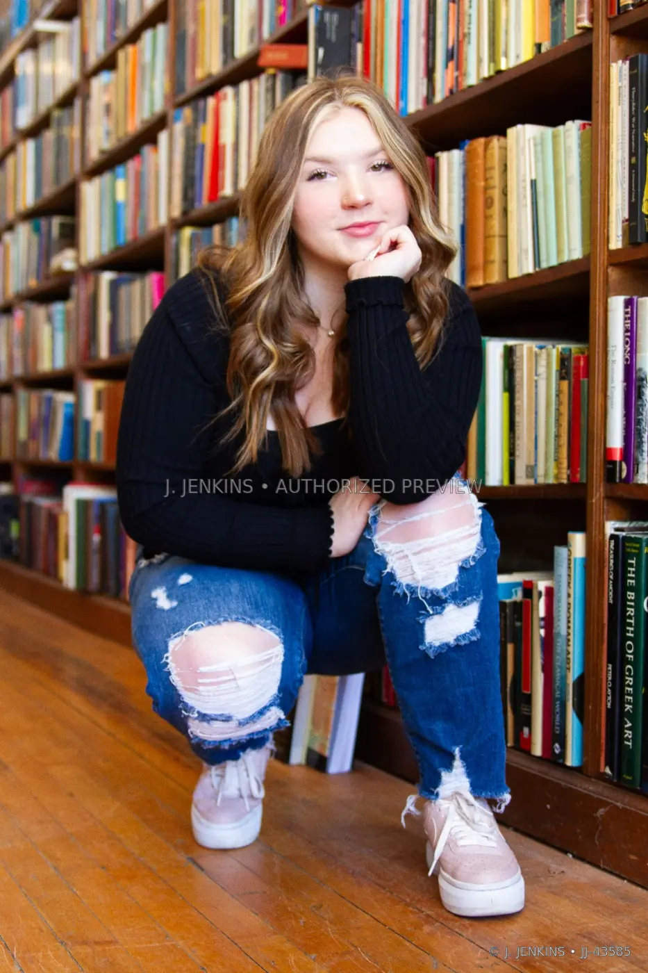Seated portrait of a young woman framed by library shelves