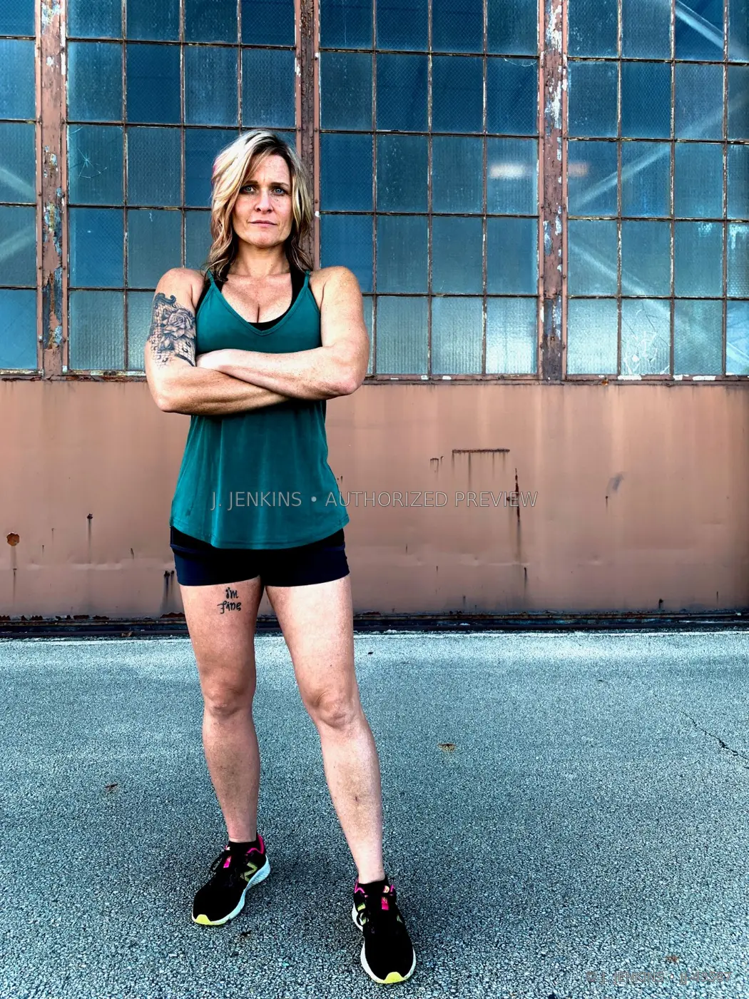 Athletic portrait of a woman standing before a wall of industrial windows