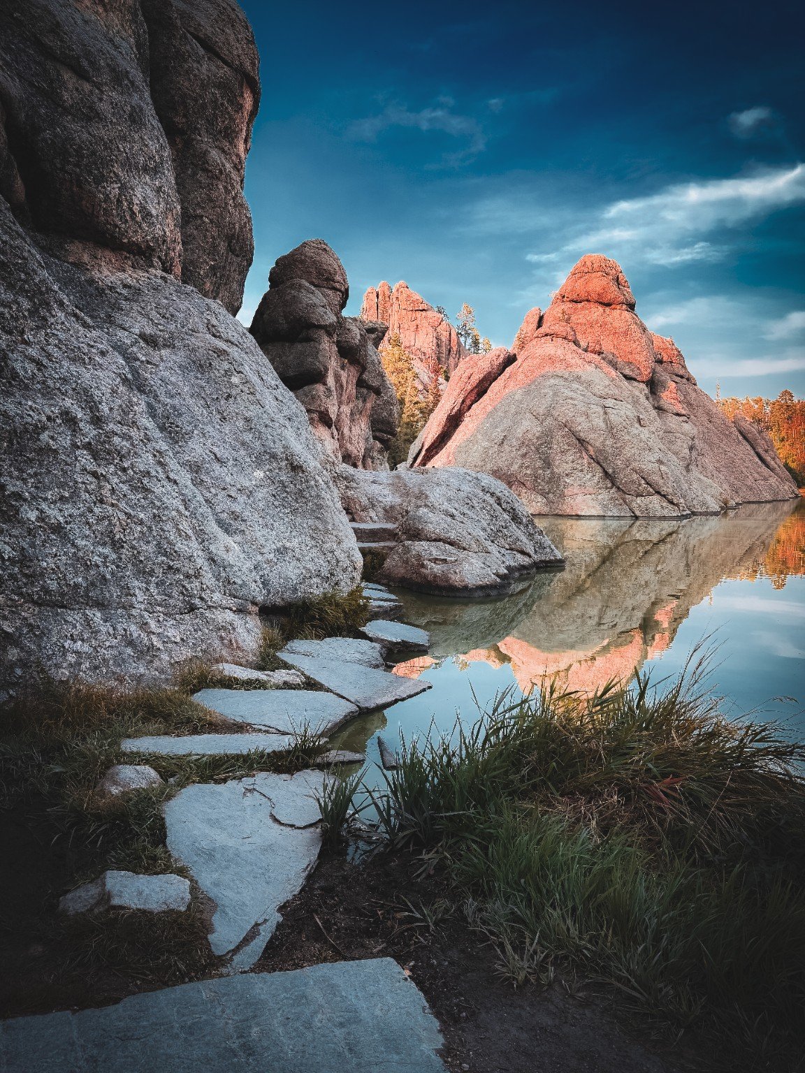Granite formations and blue sky reflected in still water