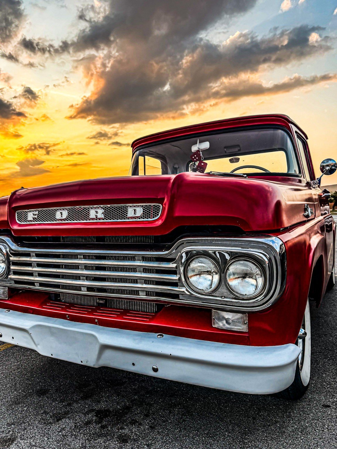 Low close portrait of a red vintage Ford truck beneath a glowing sky